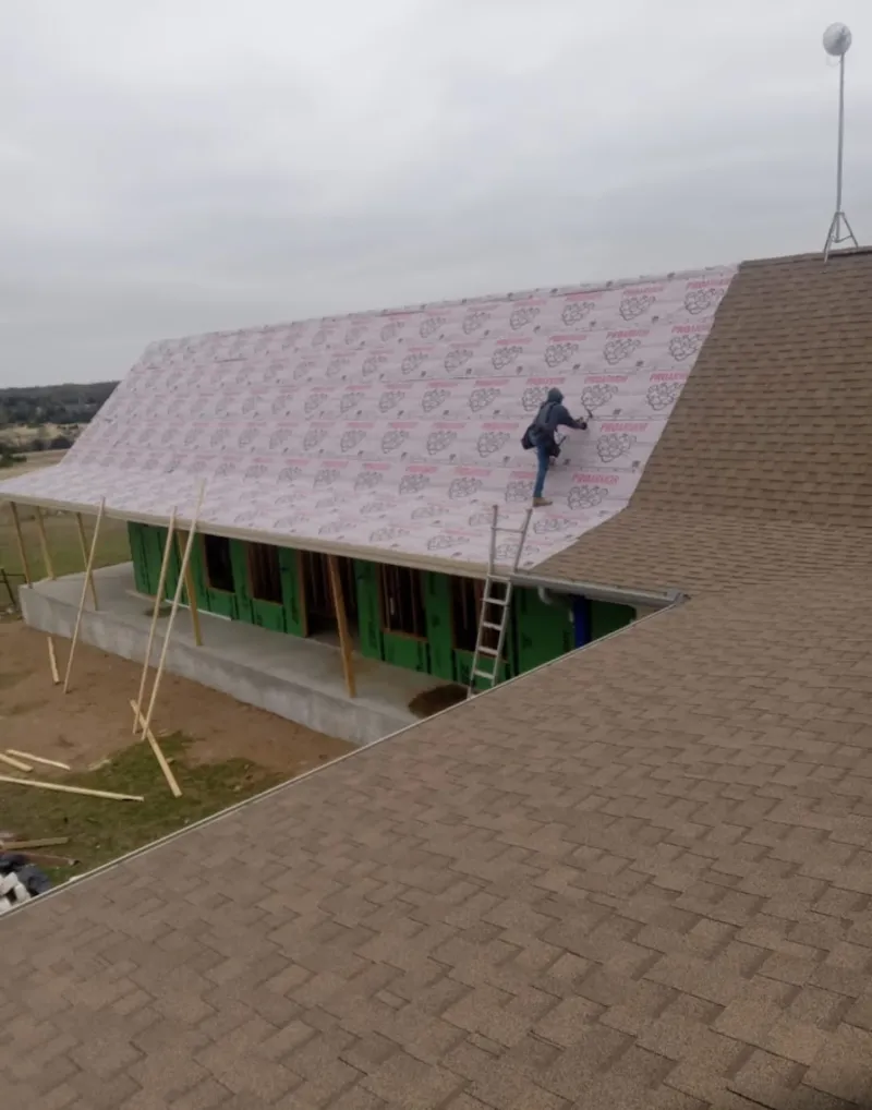 Worker preparing underlayment for a metal roof installation in Streamwood